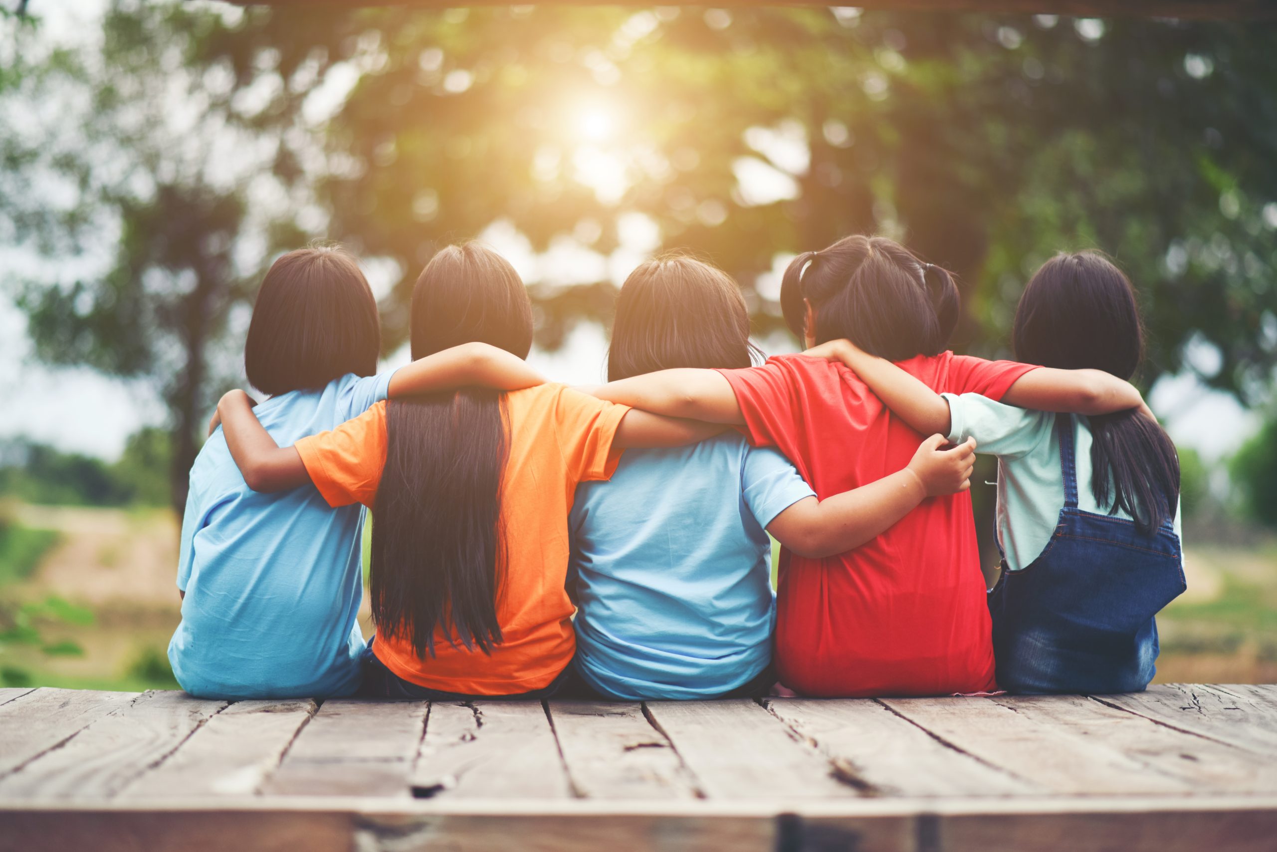 Group of kids friends arm around sitting together